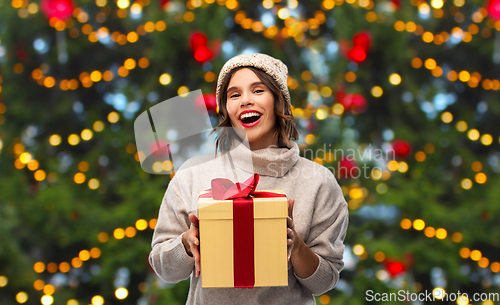 Image of happy young woman in hat holding chrismas gift