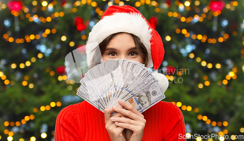 Image of happy woman in santa hat with money on christmas