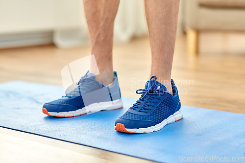 Image of close up of male feet in sneakers on exercise mat