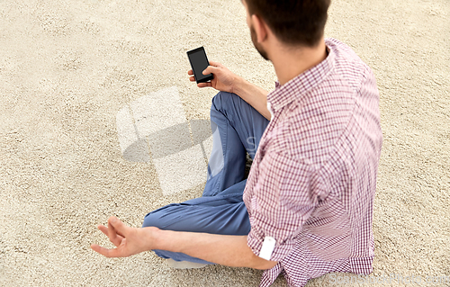 Image of close up of man with smartphone meditating at home