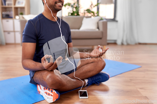 Image of indian man meditating in lotus pose at home