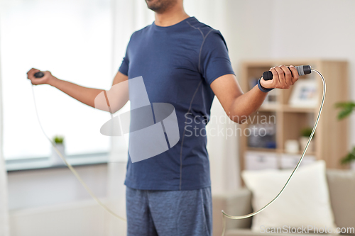 Image of man exercising with jump rope at home