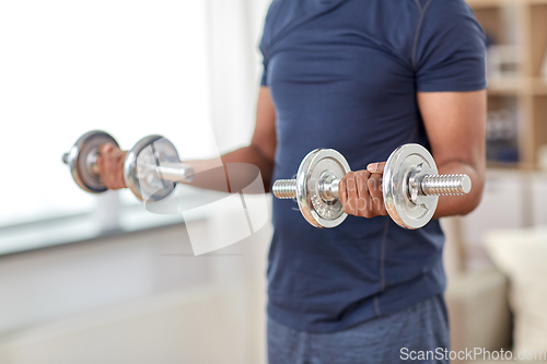 Image of man exercising with dumbbells at home