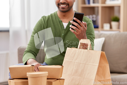 Image of indian man with takeaway food and phone at home