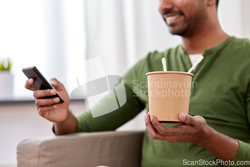 Image of indian man with phone eating takeaway food at home