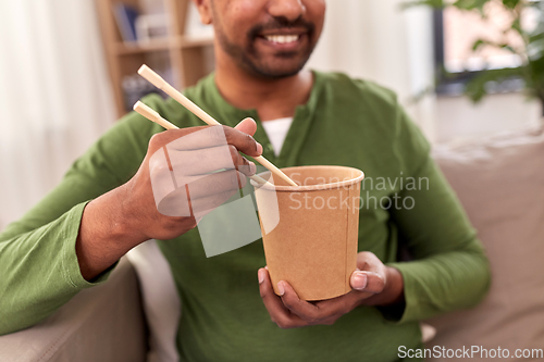 Image of smiling indian man eating takeaway food at home