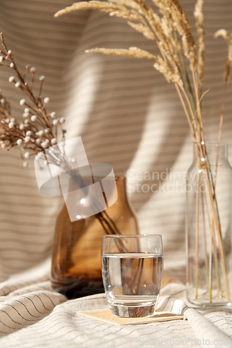 Image of glass of water, decorative dried flowers in vases