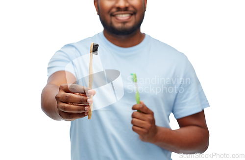 Image of man comparing wooden and plastic toothbrushes