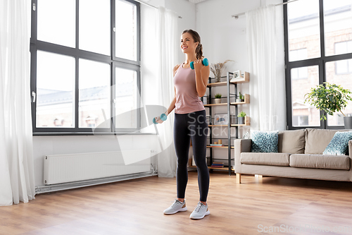 Image of smiling young with dumbbells exercising at home