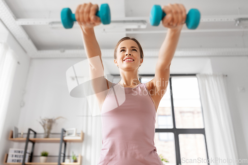 Image of smiling young with dumbbells exercising at home