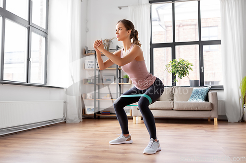 Image of woman exercising with resistance band at home