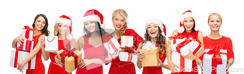 Image of happy women in santa hats with christmas gifts