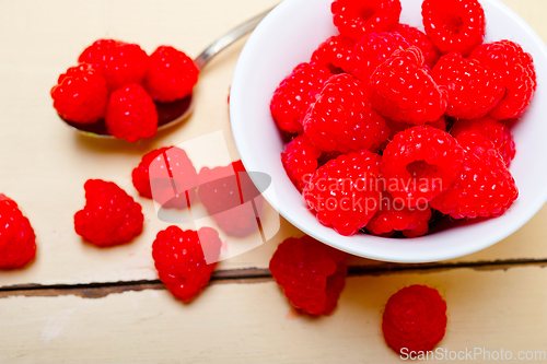 Image of bunch of fresh raspberry on a bowl and white table