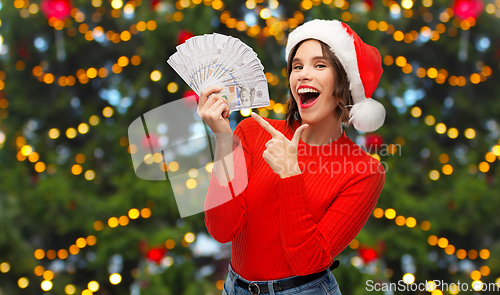 Image of happy woman in santa hat with money on christmas