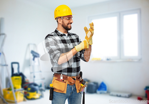 Image of happy male worker or builder in helmet and gloves