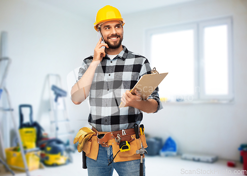 Image of happy builder with clipboard calling on smartphone