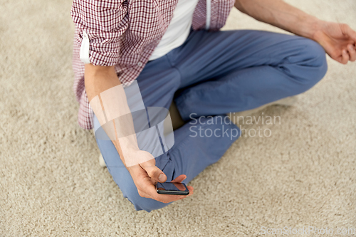 Image of close up of man with smartphone meditating at home