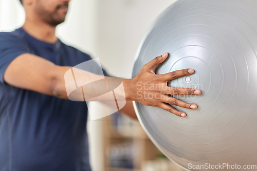 Image of man exercising and doing squats with ball at home