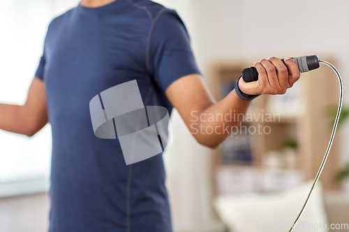 Image of man exercising with jump rope at home