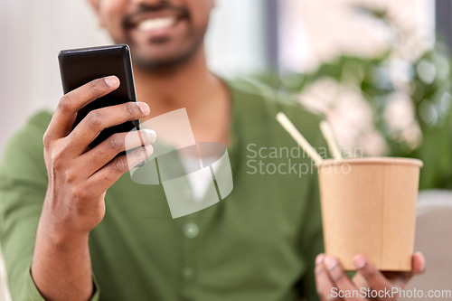 Image of indian man with phone eating takeaway food at home