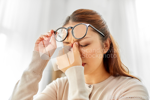 Image of tired asian woman with glasses rubbing nose bridge