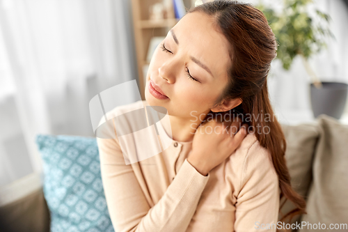 Image of asian woman suffering from ache in neck at home