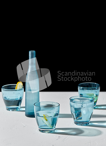 Image of glasses with water and lemons on white background