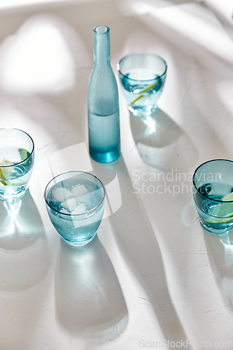 Image of glasses with water and lemons on white background