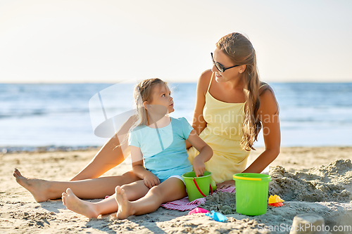 Image of mother and daughter playing with toys on beach