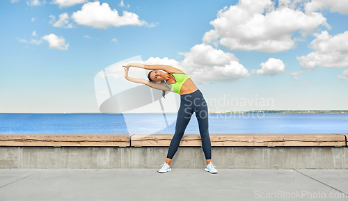 Image of young woman doing sports and stretching outdoors