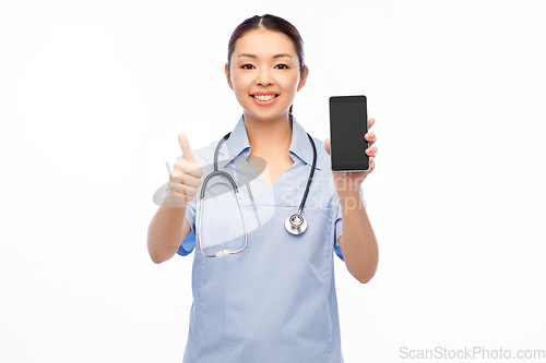 Image of asian female nurse with smartphone shows thumbs up