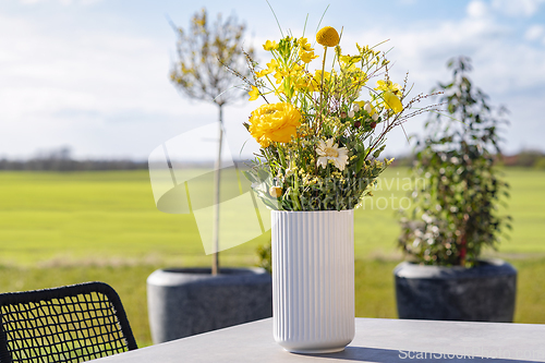 Image of Yellow wildflowers in a white vase