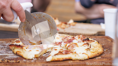 Image of Homemade pizza being sliced on a wooden board