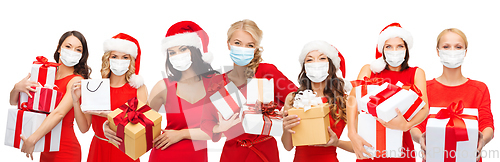 Image of happy women in medical masks with christmas gifts