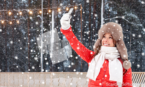 Image of happy woman taking selfie in winter at ice rink