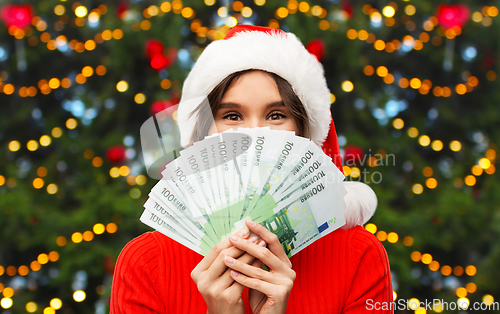 Image of happy woman in santa hat with money on christmas