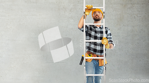 Image of male builder in helmet climbing up ladder