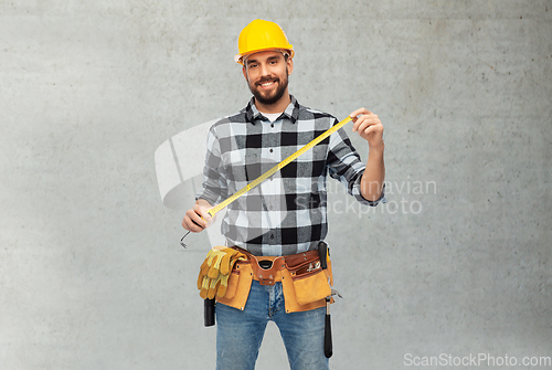 Image of happy male worker or builder in helmet with ruler