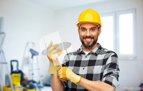 Image of happy male worker or builder in helmet and gloves