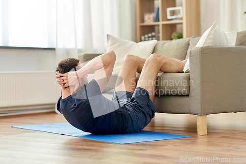 Image of man making abdominal exercises at home