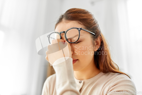 Image of tired asian woman with glasses rubbing nose bridge