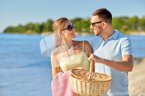 Image of happy couple with picnic basket on summer beach