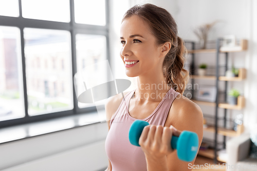 Image of smiling young with dumbbells exercising at home