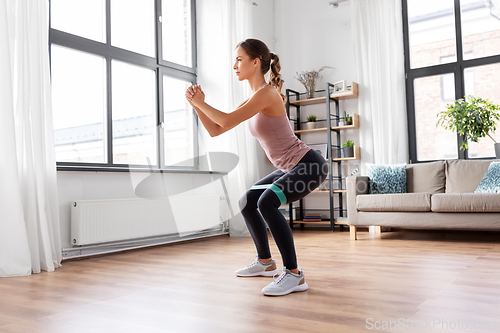Image of woman exercising with resistance band at home