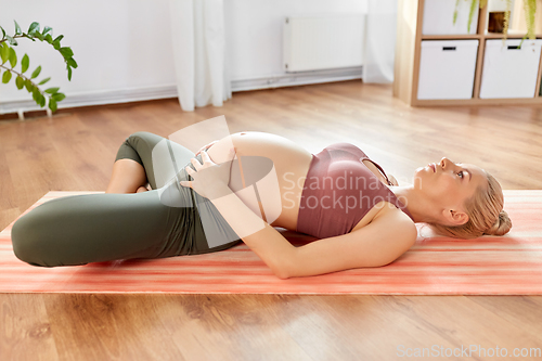 Image of happy pregnant woman doing yoga at home