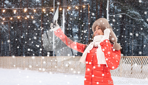 Image of woman in winter fur hat with tablet pc at ice rink