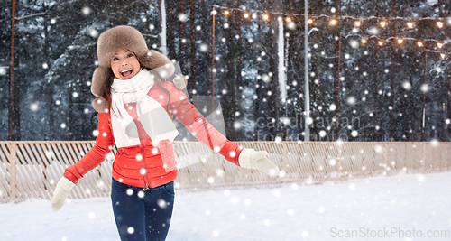 Image of happy woman in winter hat having fun at ice rink