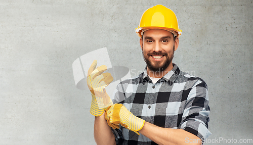 Image of happy male worker or builder in helmet and gloves