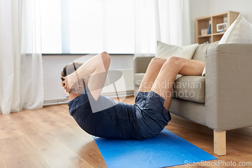 Image of man making abdominal exercises at home