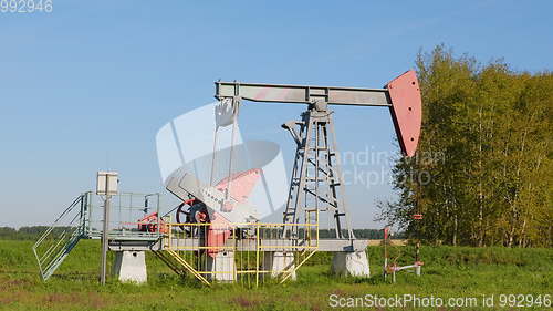 Image of Operating oil and gas well in oil field, profiled against the blue sky